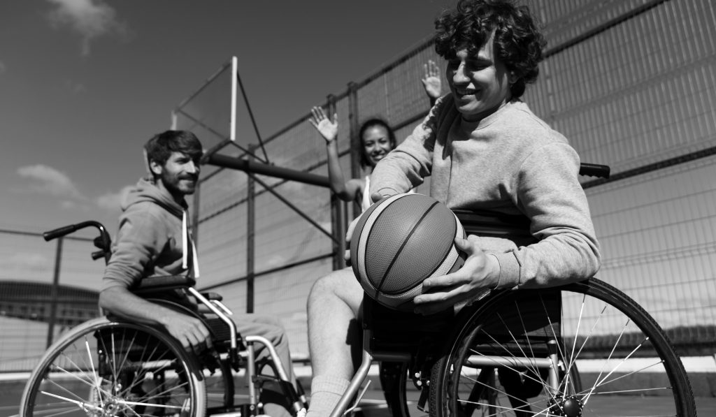 happy friends playing basketball in wheelchairs