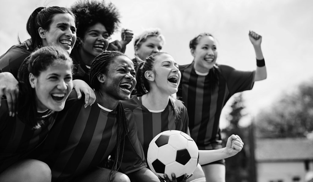 Cheerful women's soccer team screaming while celebrating winning the championship.